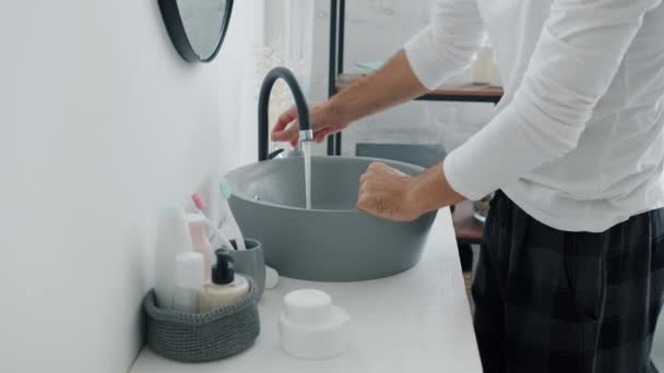 Attraente ragazzo lavarsi le mani e il viso poi accarezzare i capelli guardando specchio in bagno — Video Stock