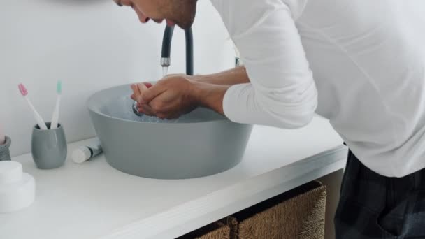 Όμορφος μελαχρινός πλένει τα χέρια και το πρόσωπο στη συνέχεια αγγίζοντας τα μαλλιά κοιτάζοντας καθρέφτη στο μπάνιο — Αρχείο Βίντεο