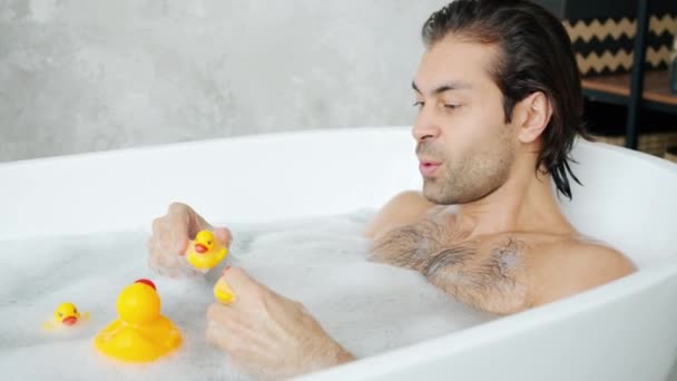 Homme de race mixte adulte ayant avec des jouets jouant avec des canards en caoutchouc dans la baignoire — Video