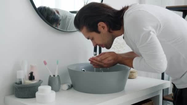 Αργή κίνηση του νεαρού άνδρα πλύσιμο προσώπου στη συνέχεια αγγίζοντας τα μαλλιά στο μπάνιο στο σπίτι — Αρχείο Βίντεο