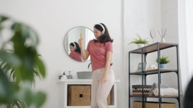 Banyoda dans eden, kulaklıkla müzik dinleyen güzel bir kadının yavaş çekimleri.