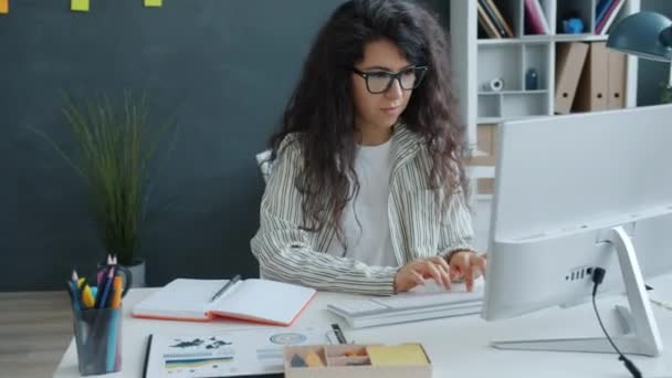 Slow motion av ganska blandad ras flicka med hjälp av dator skriva i moderna kontor — Stockvideo