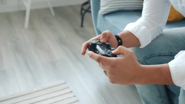 Крупный план эмоционального смешанного расового человека, играющего в видеоигры, нажимающего кнопки джойстика дома — стоковое видео