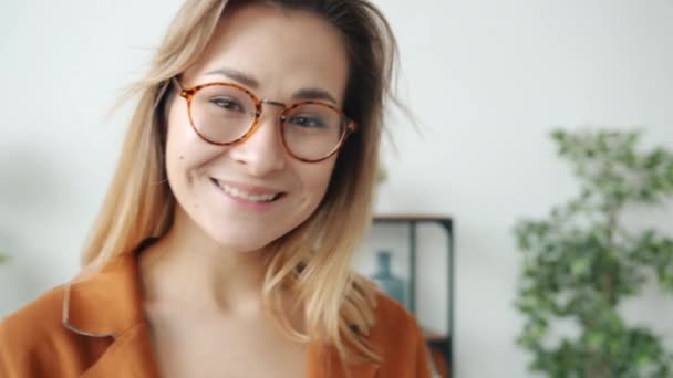Retrato de mujer joven atractiva mirando a la cámara con sonrisa feliz en el apartamento — Vídeos de Stock