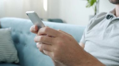 Şapka giyen bir adamın kapalı mekanda sesli mesajlar kaydettiği yakın plan.