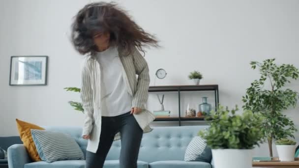 一人で家で音楽を聴いて飛び跳ねる若い女性 — ストック動画