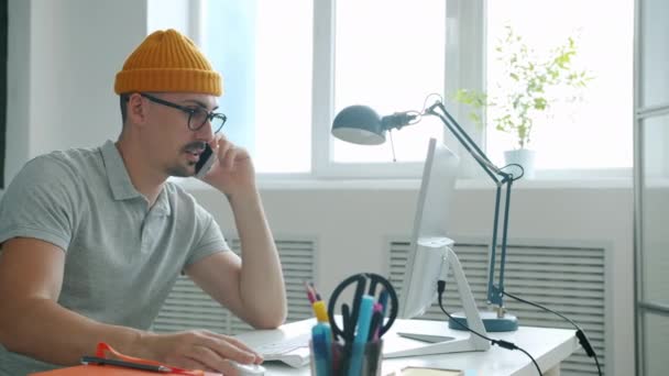 Vrolijke jonge kantoormedewerker in gesprek op mobiele telefoon over zaken op het werk — Stockvideo