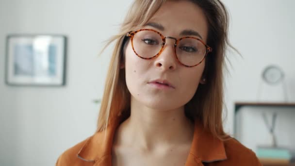 Retrato de cerca de la chica mirando a la cámara con cara seria y luego sonriendo en el interior — Vídeos de Stock