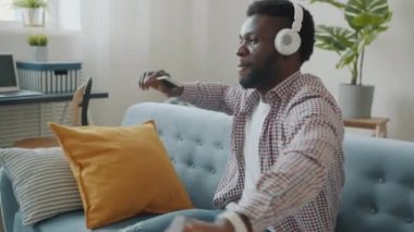 Mutlu Afrikalı Amerikalı adam evde dans eden kulaklıklarla müzik dinleyerek eğleniyor.