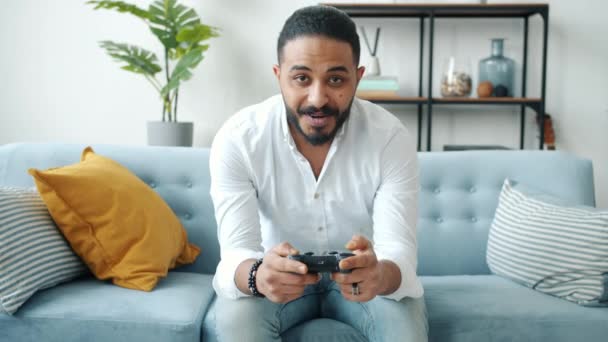 Porträt eines fröhlichen Mannes aus dem Nahen Osten beim Vido-Spiel mit Joystick zu Hause — Stockvideo
