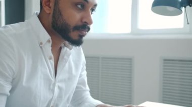 Ofis odasındaki bilgisayarla online işle meşgul olan ciddi bir iş adamı daktilo kullanıyor.