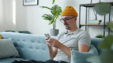 Akıllı telefon mesajları kullanan mutlu adamın yavaş çekim gülüşü evde iletişimin keyfini çıkarıyor.