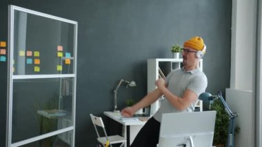Ofiste dans eden neşeli iş adamı kulaklıkla müzik dinliyor iş yerinde eğleniyor.