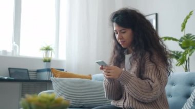 Güzel kız öğrenci akıllı telefondan iyi haberler alıyor. Evdeki cihazı kullanarak gülümsüyor.