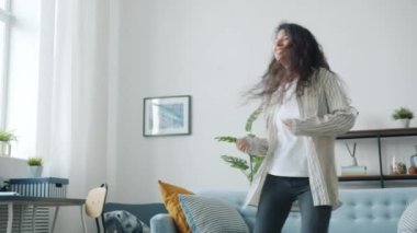 Genç ve güzel bir esmerin dans etmesi ve apartmanda müzik dinlemesi.