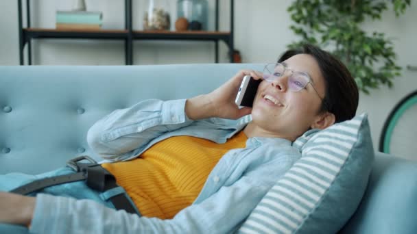 Movimento lento da jovem falando no celular e sorrindo recebendo boas notícias em casa — Vídeo de Stock