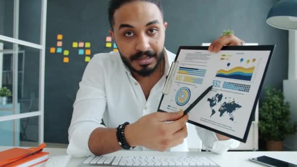 Porträt eines Mannes mit gemischter Rasse, der während einer Online-Videokonferenz im Büro redet und Diagramme zeigt — Stockvideo