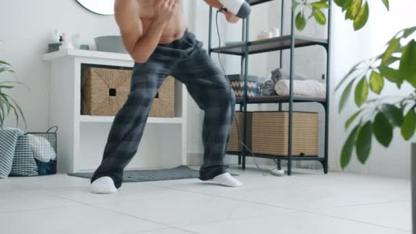 Lassú mozgás játékos vegyes verseny férfi táncol a fürdőszobában hajszárítóval szórakozás egyedül — Stock videók