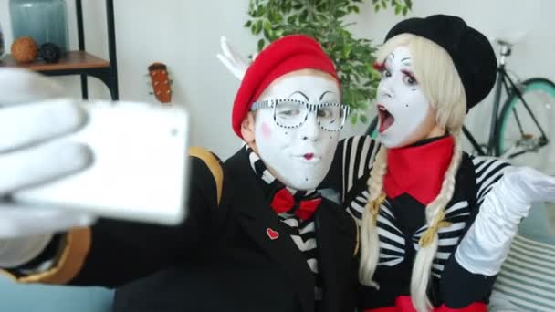 Casal alegre de mimes tirando selfie com câmera de smartphone mostrando gesto de polegar para cima em casa — Vídeo de Stock