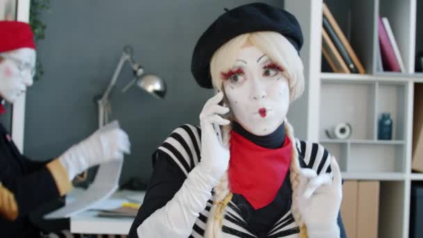 Moody flicka mima talar på mobiltelefon skriker sedan ler skicka luft kyss på kontoret — Stockvideo