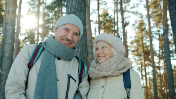 Портрет красивой пожилой пары мужчина и женщина смотрят друг на друга, затем на камеру в зимнем парке — стоковое видео