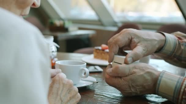 Primo piano delle mani delle donne anziane che prendono l'anello dal portagioie durante il pranzo con l'uomo nel ristorante — Video Stock
