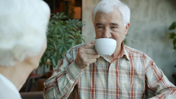 Senior muž mluví se šťastnou ženou a pití čaje těší čas oběda v kavárně — Stock video