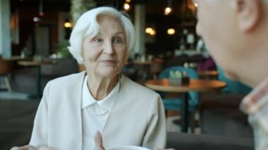 Zarif kıyafetler içinde, kocasıyla konuşan ve restoranda çay içen güzel bir son sınıf öğrencisi.