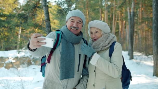 Cámara lenta del hombre y la mujer mayores tomando selfie en el parque de invierno usando la cámara del teléfono inteligente — Vídeo de stock