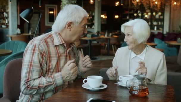 Radosny starszy mężczyzna i kobieta dobrze się bawią rozmawiając śmiejąc się przybijając piątkę przy stole w restauracji — Wideo stockowe