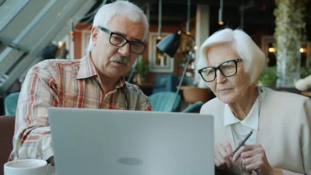 Senior zakenmensen man en vrouw praten op zoek naar laptop scherm in cafe — Stockvideo