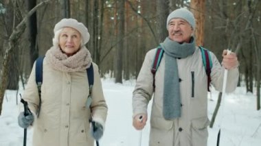 Kış günü parkta kayak yürüyüşü yaparken mutlu aile konuşmaları.