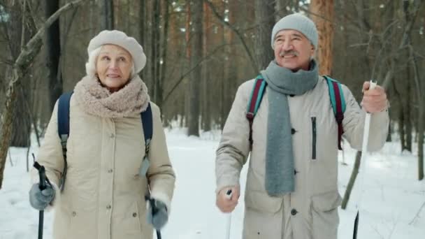 Счастливая пожилая семья разговаривает во время лыжной прогулки в парке в зимний день — стоковое видео