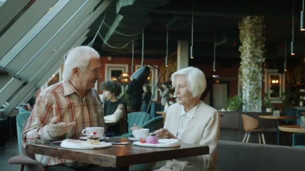 Seniorin bekommt Geschenk in dekorierter Schachtel von liebendem Ehemann im Café — Stockvideo