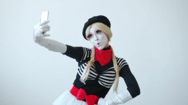 Güzel kız pandomimci akıllı telefon kamerasıyla selfie çekiyor gülümsüyor ve eğleniyor