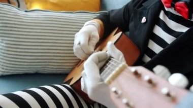 Erkek pandomimci akustik gitar çalarken kız evde eğleniyor.