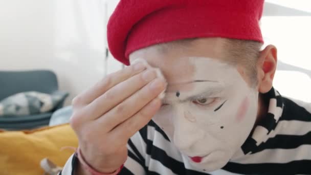 Молодий чоловік-комік видаляє фарбу для обличчя і макіяж очищає шкіру після виконання — стокове відео