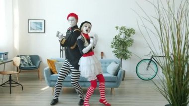 Neşeli kız ve erkek pandomimci dans ediyor. Evde eğlenceli numaralar yapıyor.