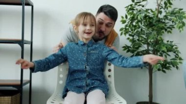 Mutlu bir babanın portresi. Sevimli bir çocukla eğleniyor. Sandalyesini itiyor, gülüyor.