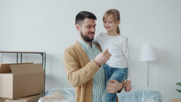 Otec drží dceru v rukou ukazující klíč k novému bytu se usmívá těší přemístění — Stock video