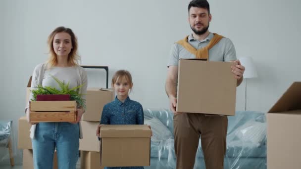 Retrato de pais e crianças bonitos segurando caixas olhando para câmera com rostos felizes durante a realocação — Vídeo de Stock