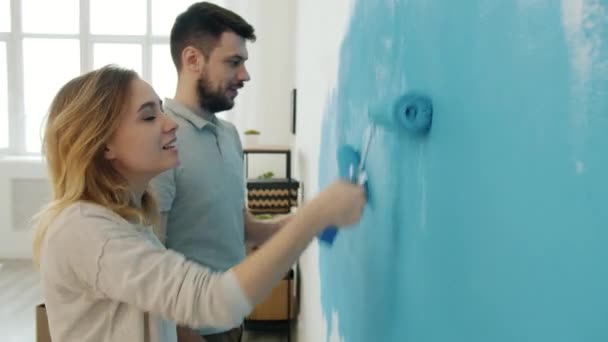 Pareja feliz con narices cubiertas de pintura besando y riendo pared de pintura en el apartamento — Vídeos de Stock