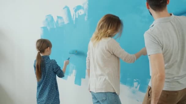 Back view of couple with kid painting wall at home and dancing renovating apartment — Stock Footage Back view of couple with kid painting wall at home and dancing renovating apartment Video Clip