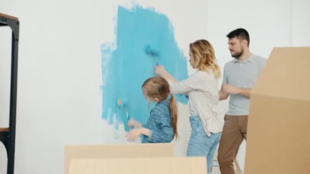 Little girl painting wall with parents dancing and having fun enjoying music indoors at home — Stock Footage Little girl painting wall with parents dancing and having fun enjoying music indoors at home Royalty Free Stock Video
