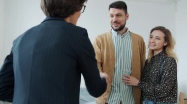 Neşeli çift emlakçıyla tokalaşıyor evin anahtarını alıyor.
