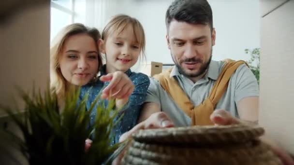 Портрет счастливой семьи с ребенком, распаковывающим вещи во время переезда, глядя на памятные вещи — стоковое видео