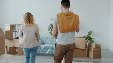 Mutlu ebeveynler ve çocuklar yeni daireye kutu taşıyorlar sonra rahatça sarılıyorlar gülümsüyorlar.
