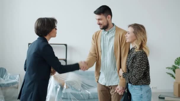 Jovem homem de família e mulher comprando casa recebendo chaves de abraço corretor de imóveis beijando — Vídeo de Stock
