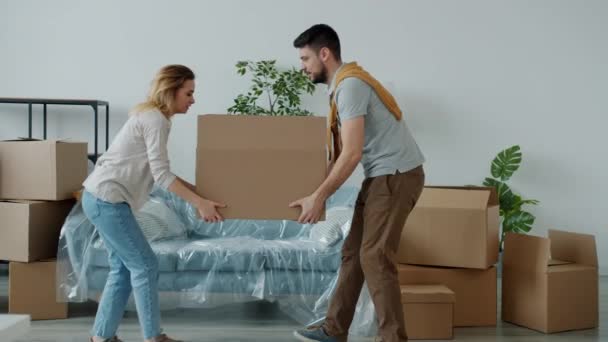 Мужчина и женщина несут тяжелые коробки в новый дом и страдают от болей в спине — стоковое видео