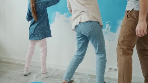 Slow motion van kleine meisje vrouw en man schilderen muur in appartement en dansen — Stockvideo